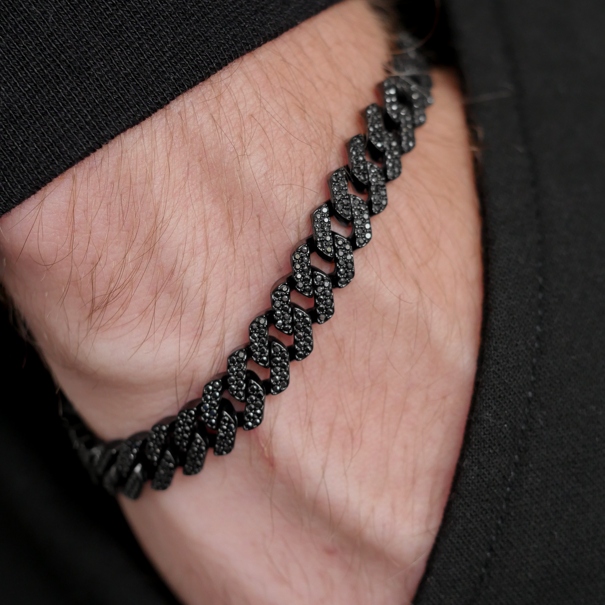 A close-up of a black chain-link gemstone bracelet worn on a person's wrist.